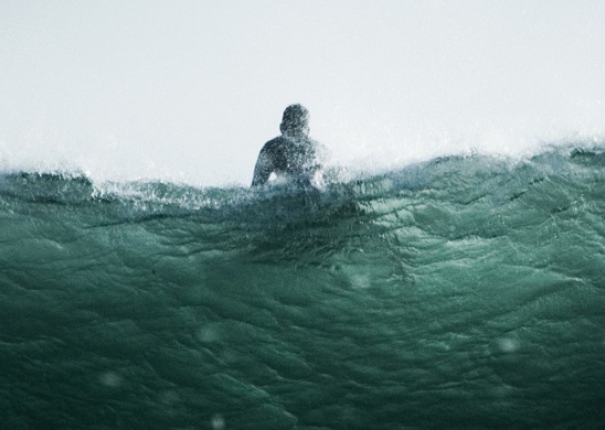 Person on a surfboard waiting for a wave shot from under the water