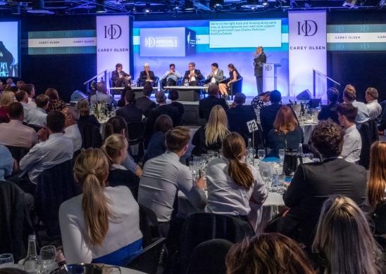 People sat at tables listening to a debate at the IoD Guernsey annual convention in 2018 